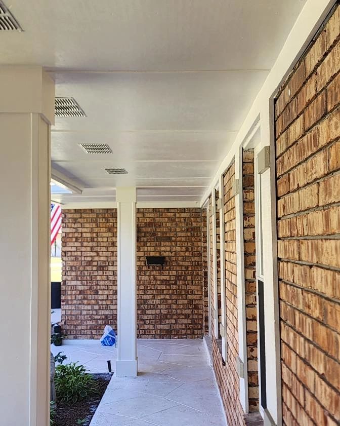Covered brick porch with white columns and a clean floor