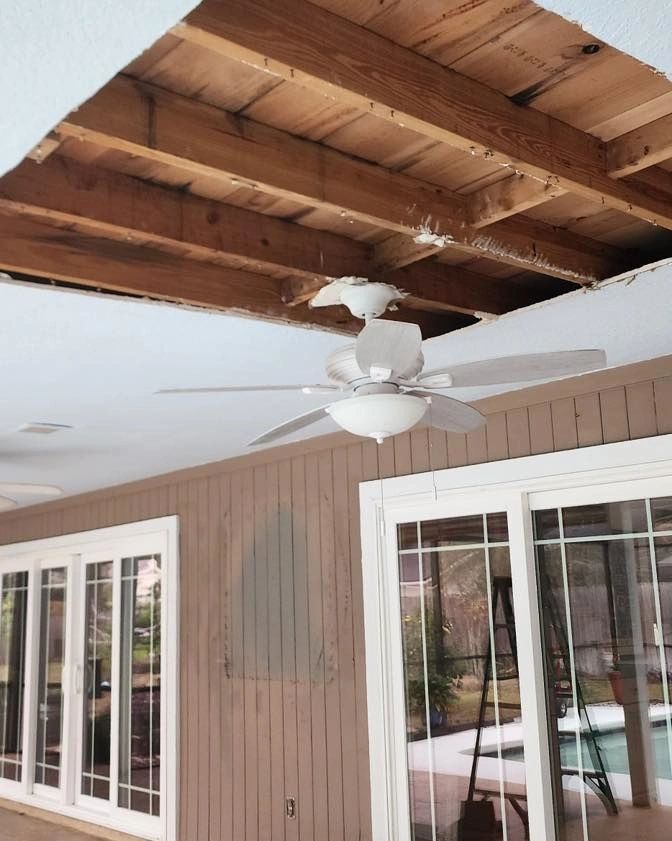 Patio ceiling opened to expose joists next to a ceiling fan