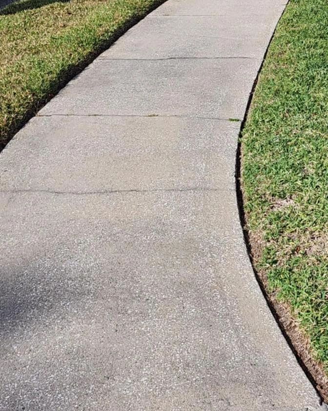 Clean concrete sidewalk curving through a lawn
